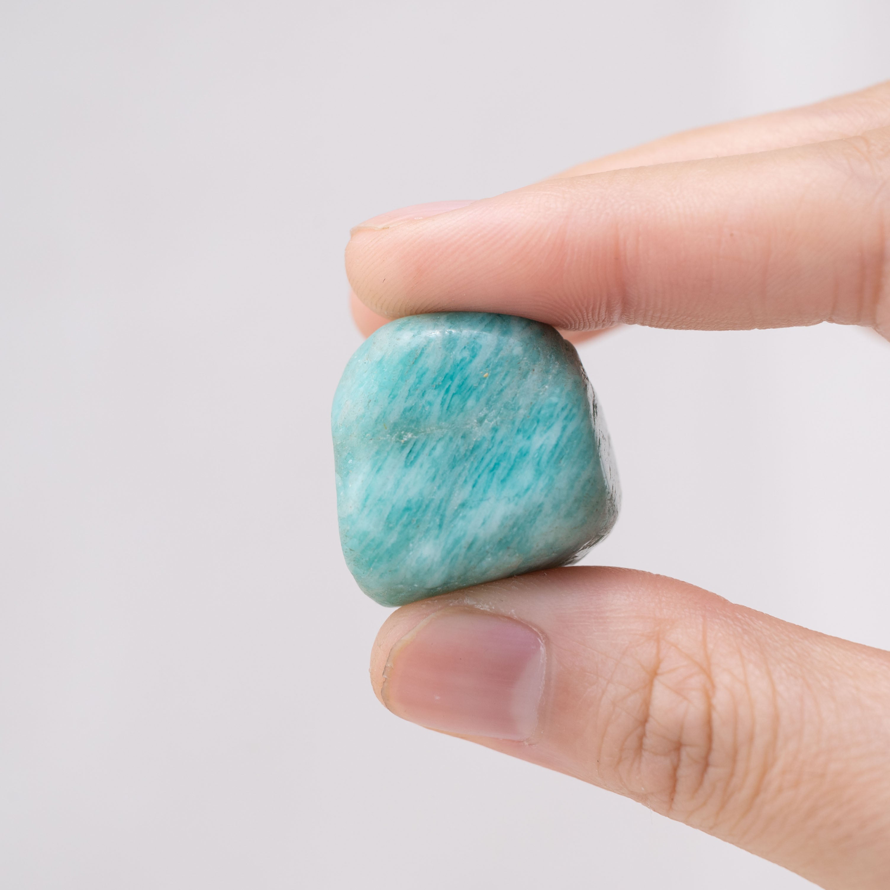 Hand holding Amazonite tumbled stone for calming energy