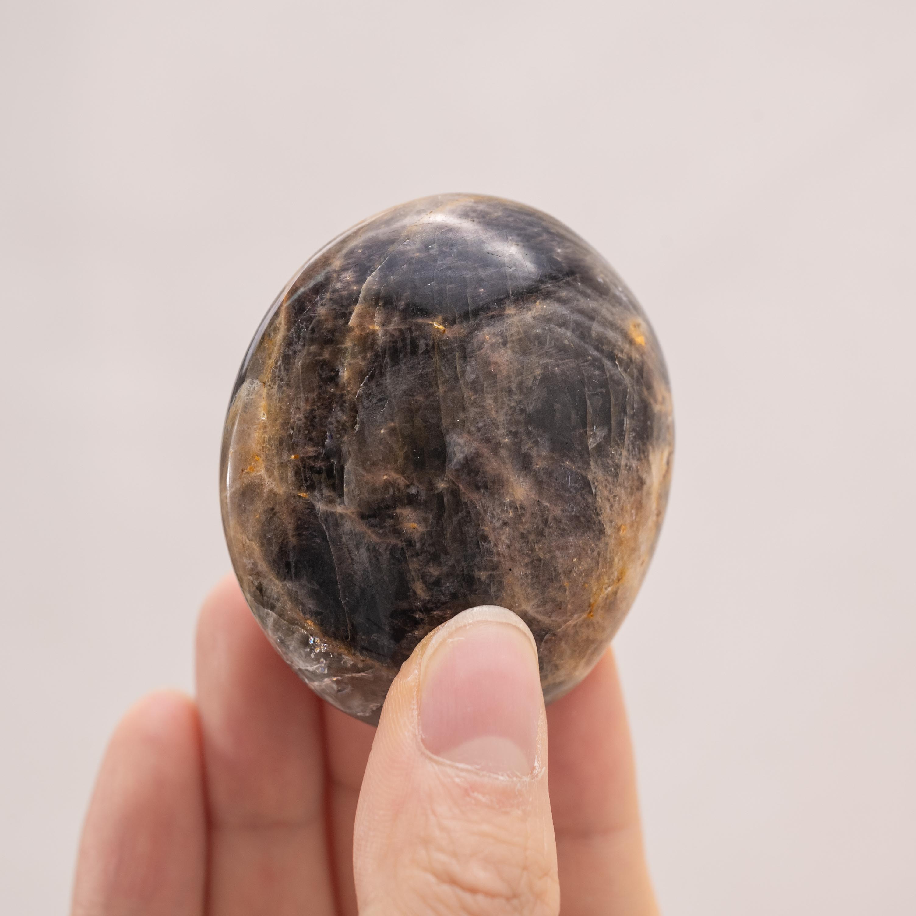 Black Moonstone held in palm reflecting soft light