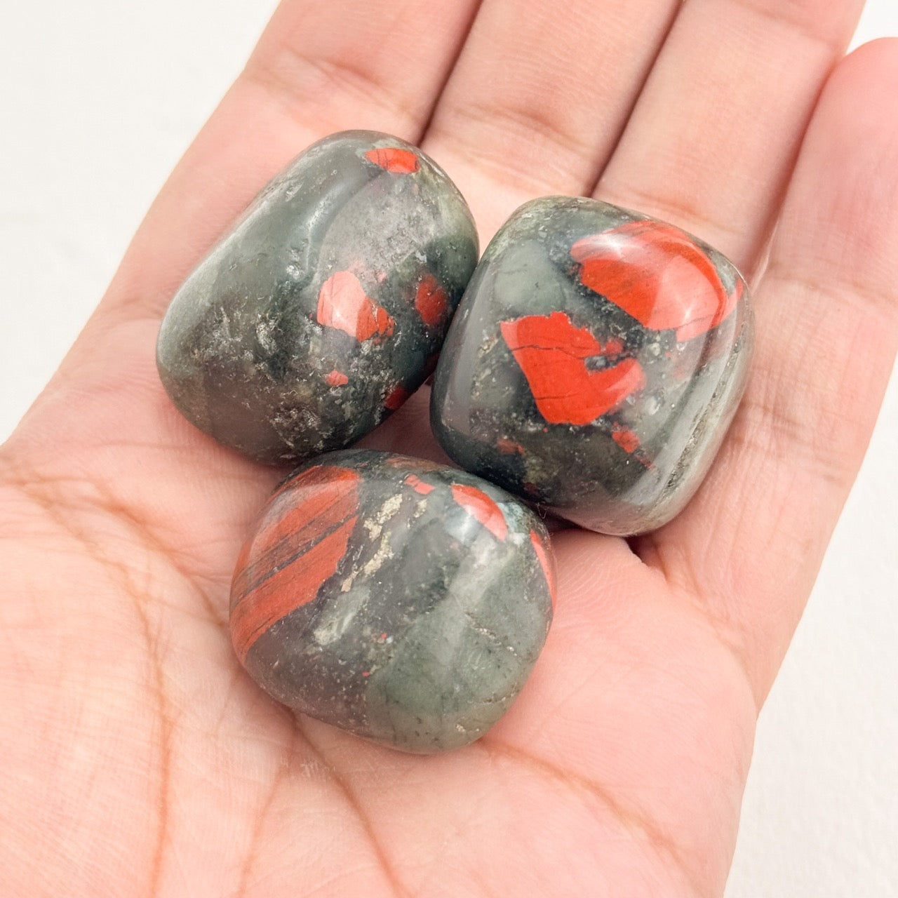 Hand holding a Bloodstone Tumble for meditation