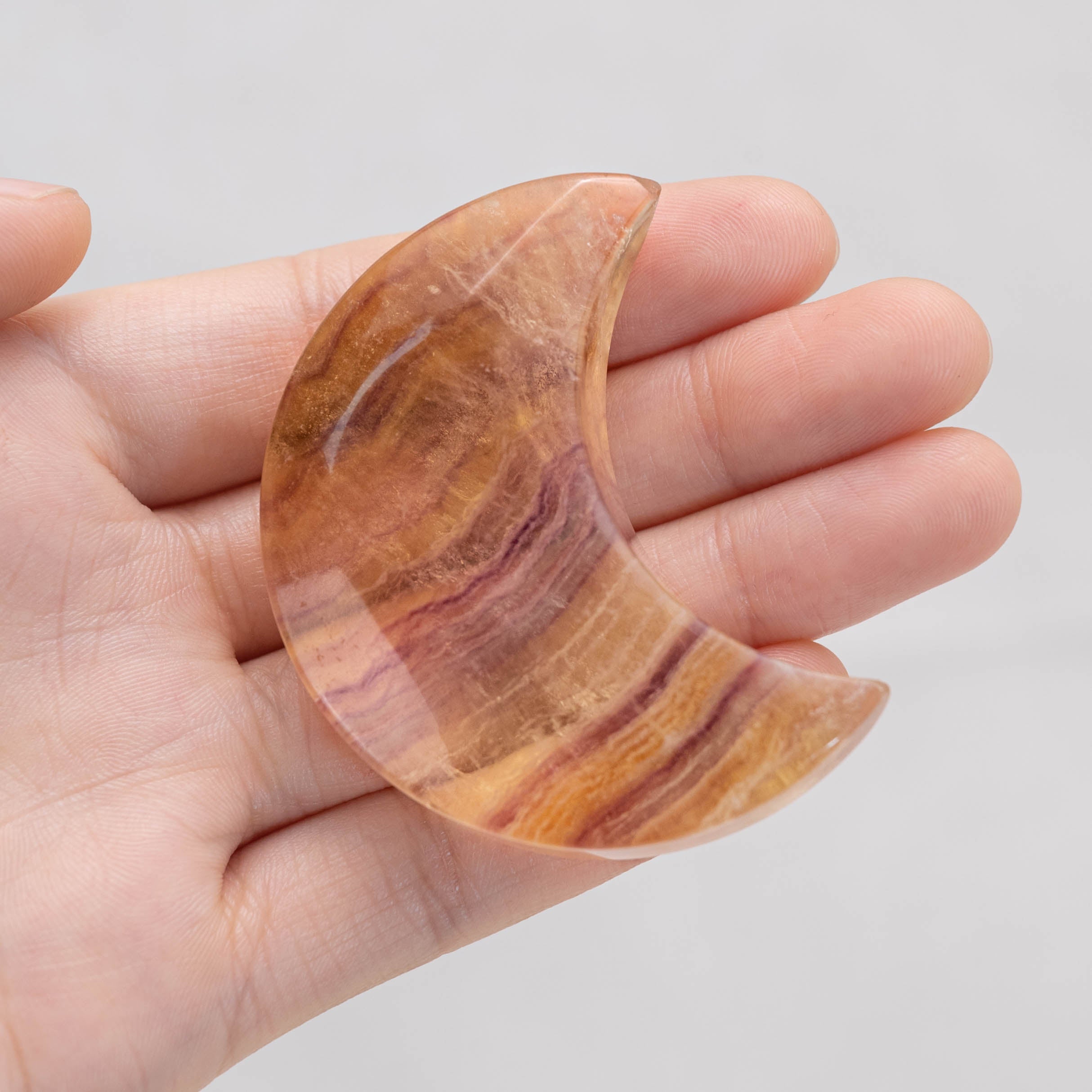 Hand holding Candy Fluorite Moon Palm Stone