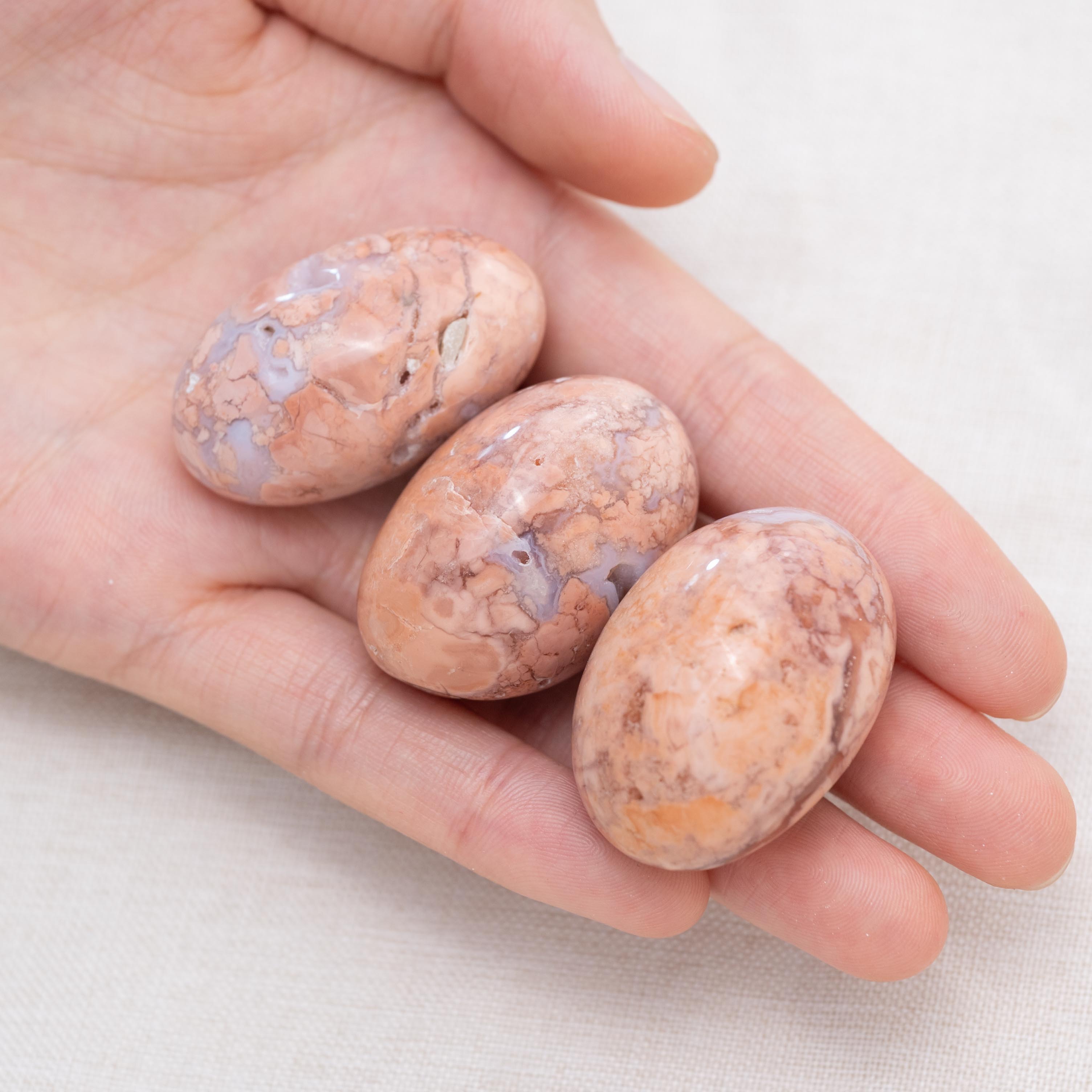 Hand holding Petal Agate tumbled stone for balance and peace