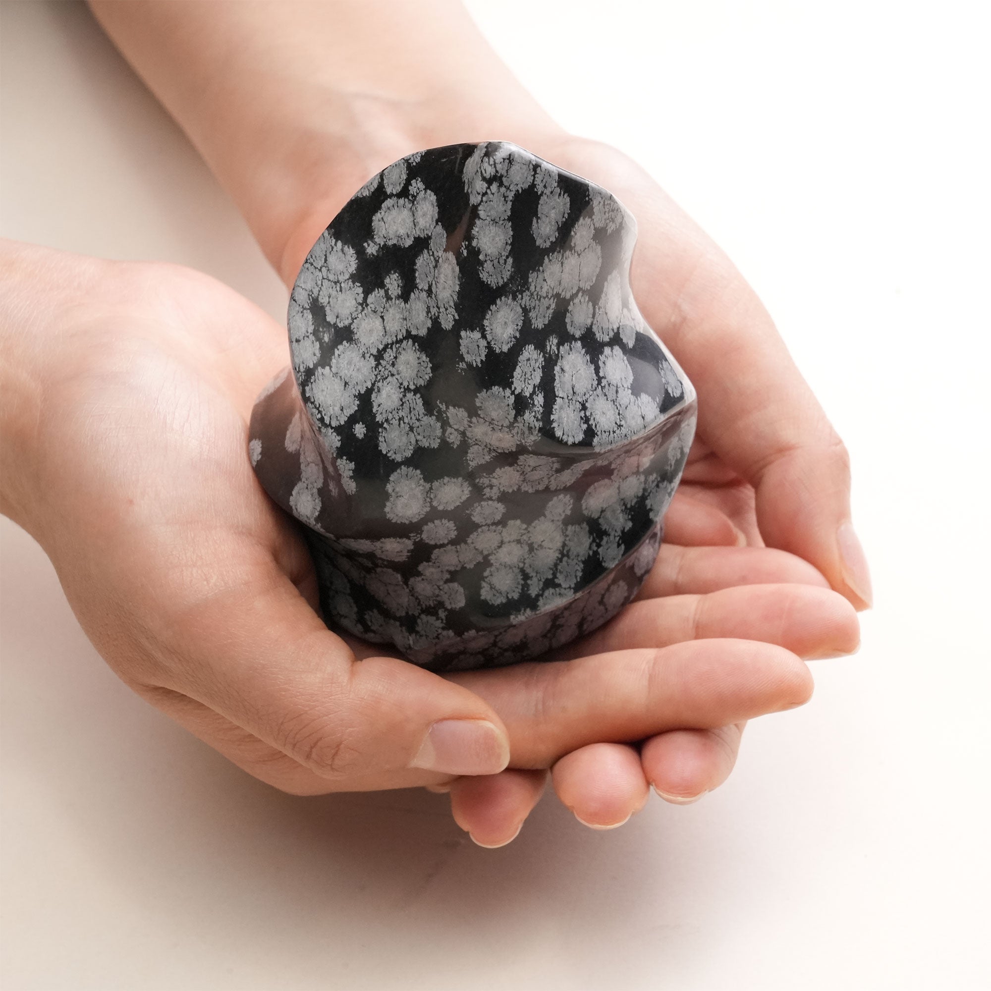 Handheld Snowflake Obsidian Flame emphasizing its smooth texture and design