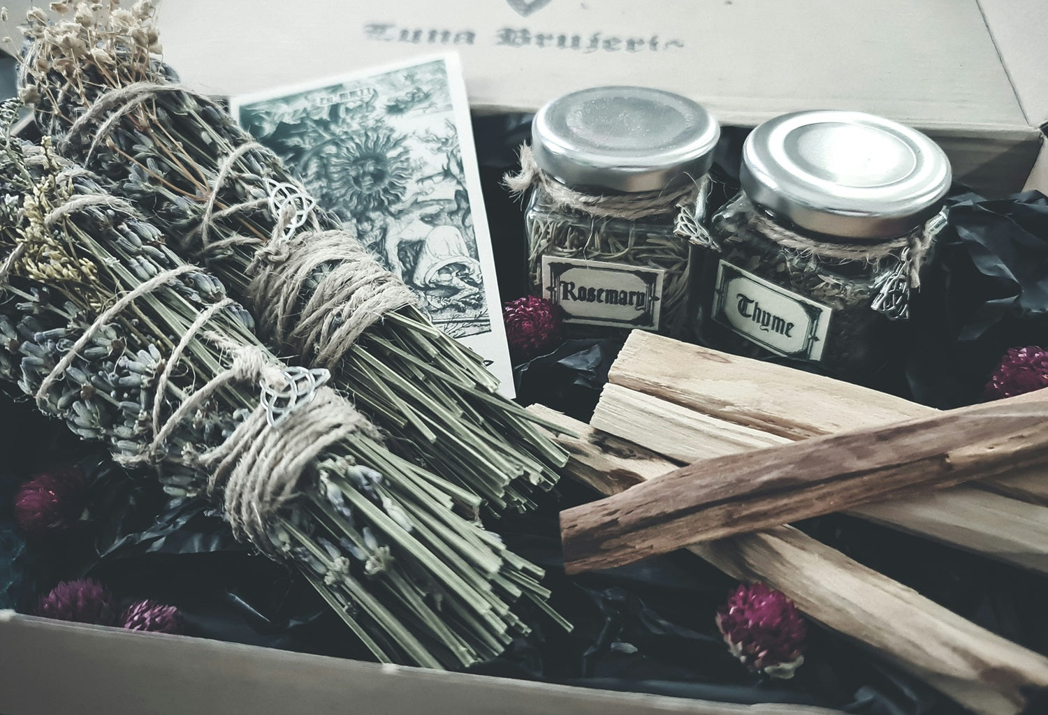 A collection of smudging herbs, including bundles of lavender and jars of rosemary and thyme, used for cleansing and purifying crystals. This method uses the smoke from these herbs to clear negative energy and revitalize the crystals.