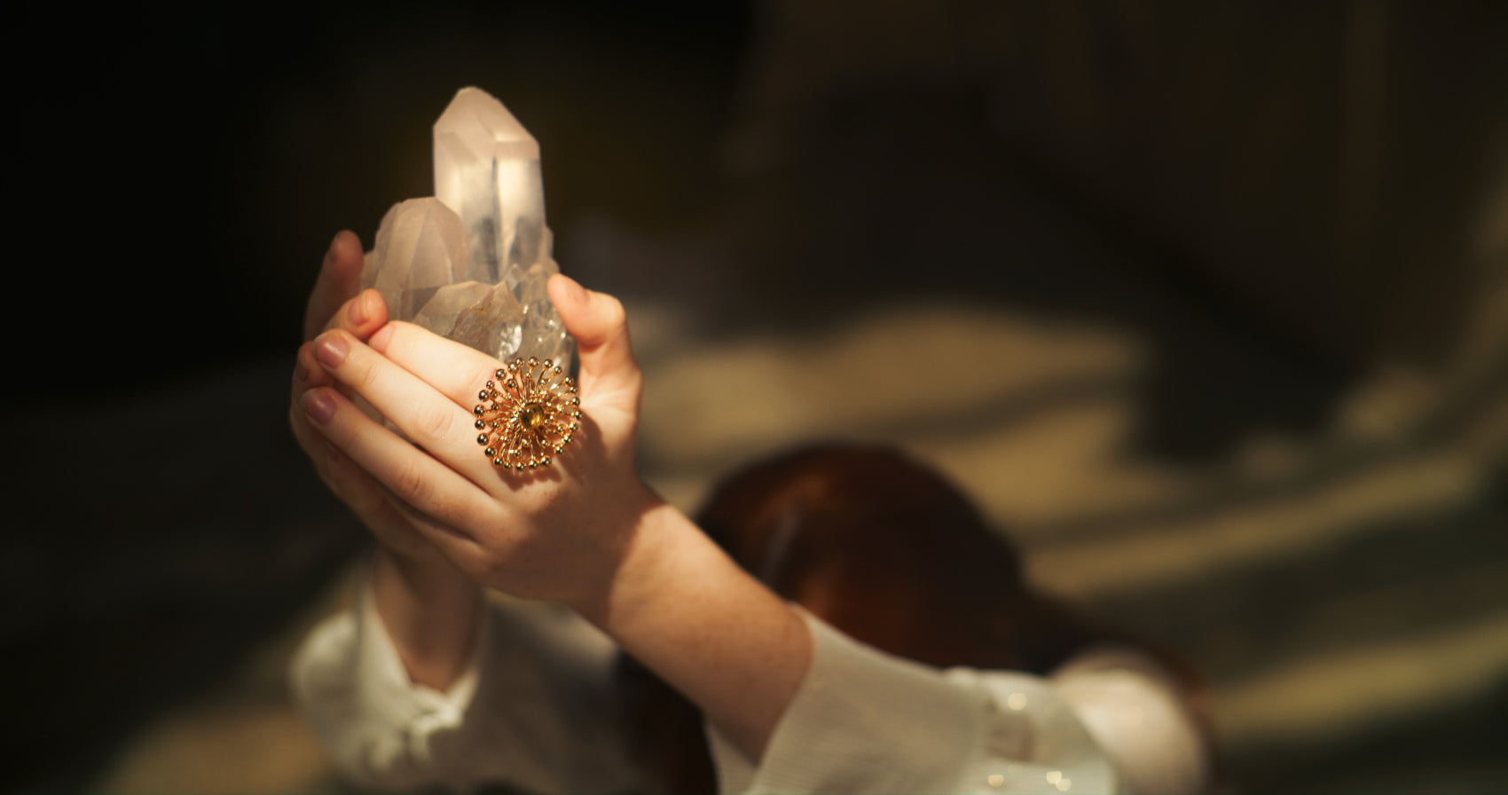A woman holding a clear quartz crystal cluster in her hands, emphasizing a moment of spiritual connection.