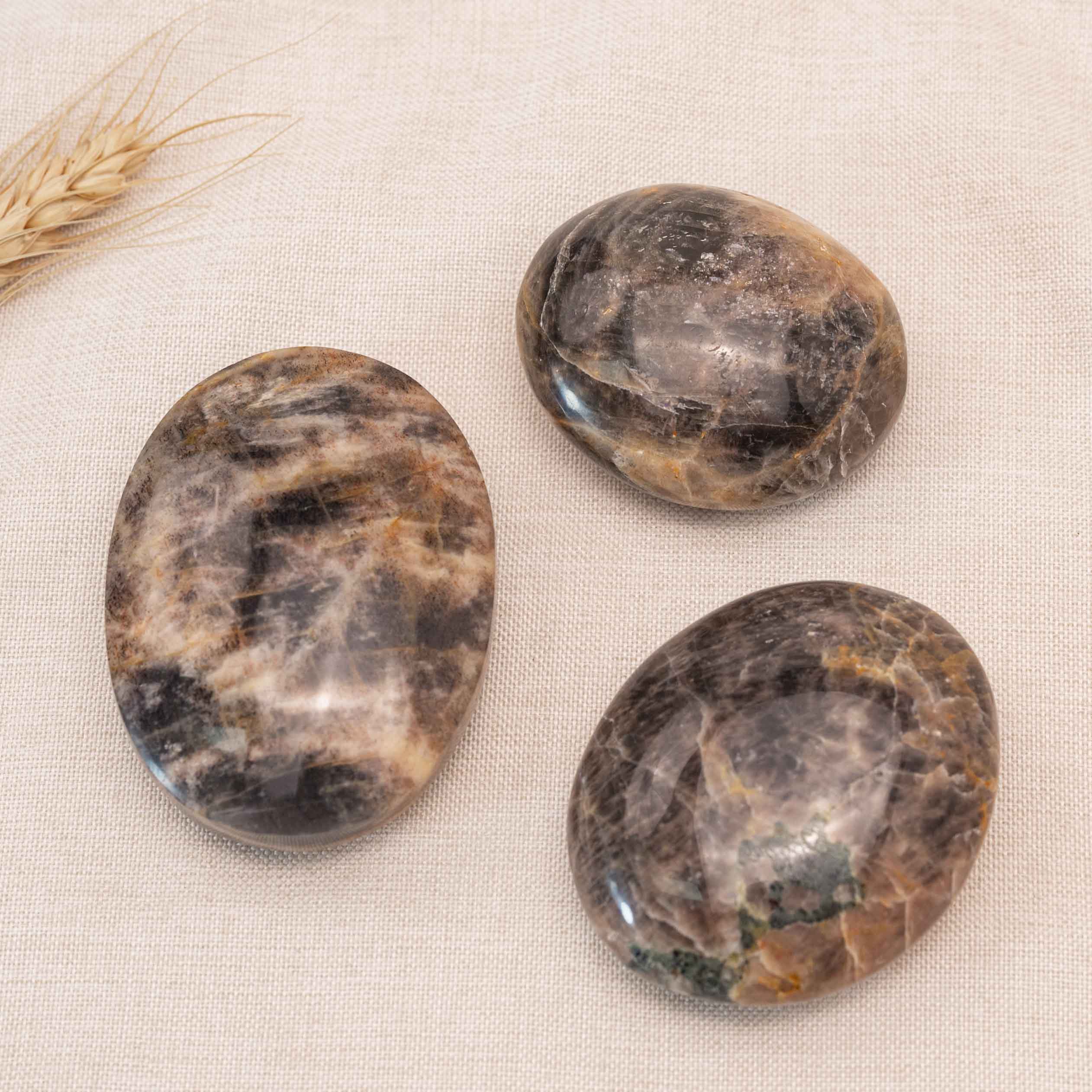 Detailed view of Black Moonstone Palmstone, highlighting its role in balancing root and crown chakras.