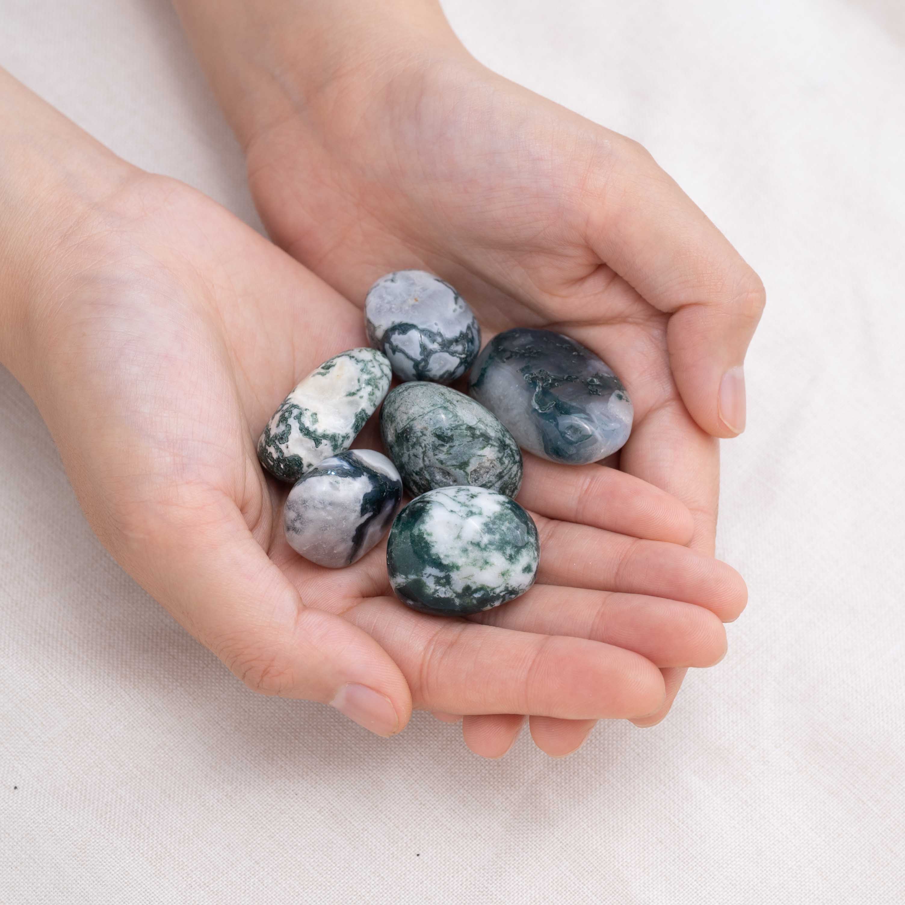 Hand cupping Moss Agate tumbled stone for abundance