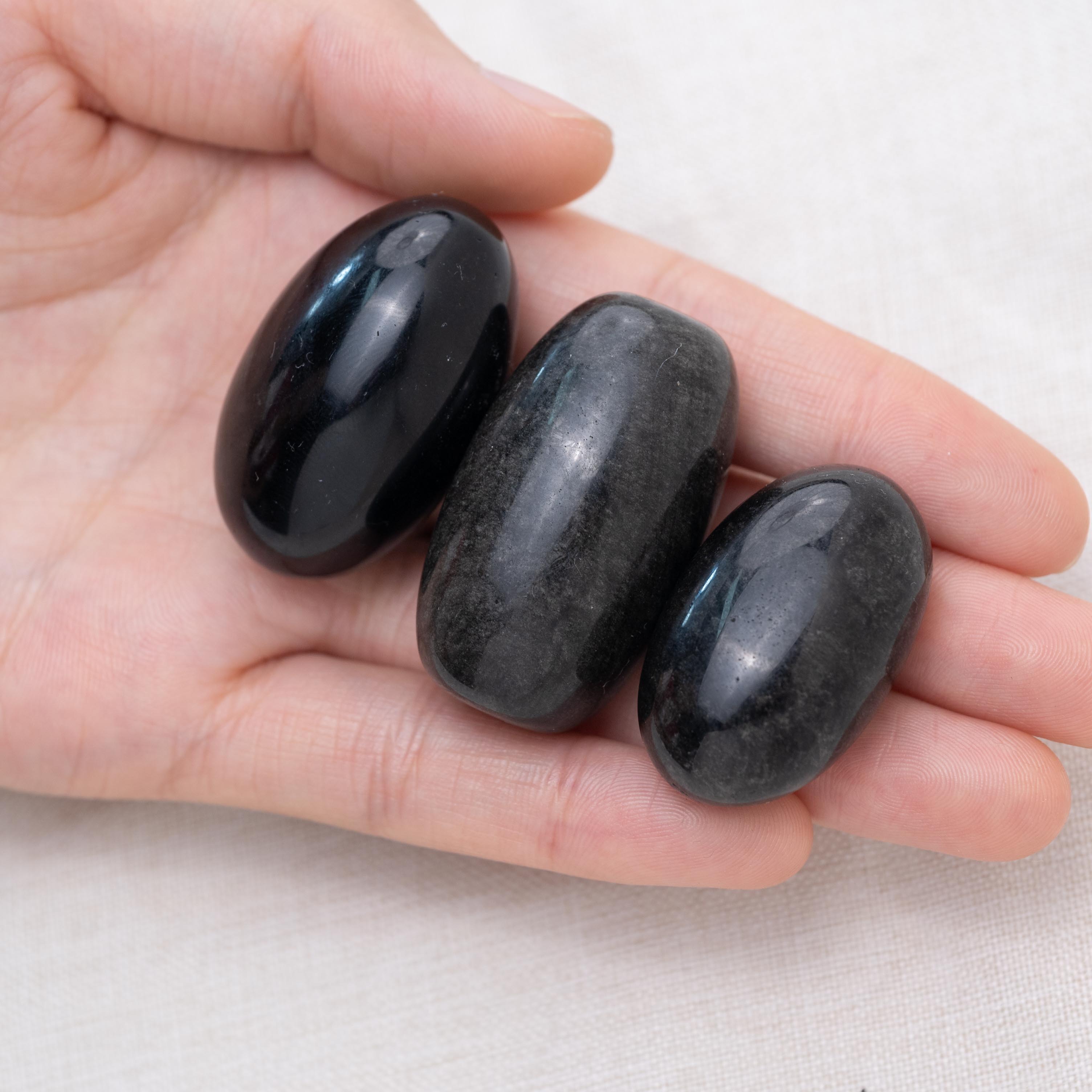 Hand holding Silver Obsidian tumbled stone for protection