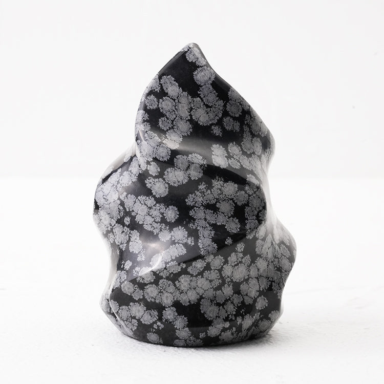 Natural Snowflake Obsidian Flame placed on a wooden surface for contrast