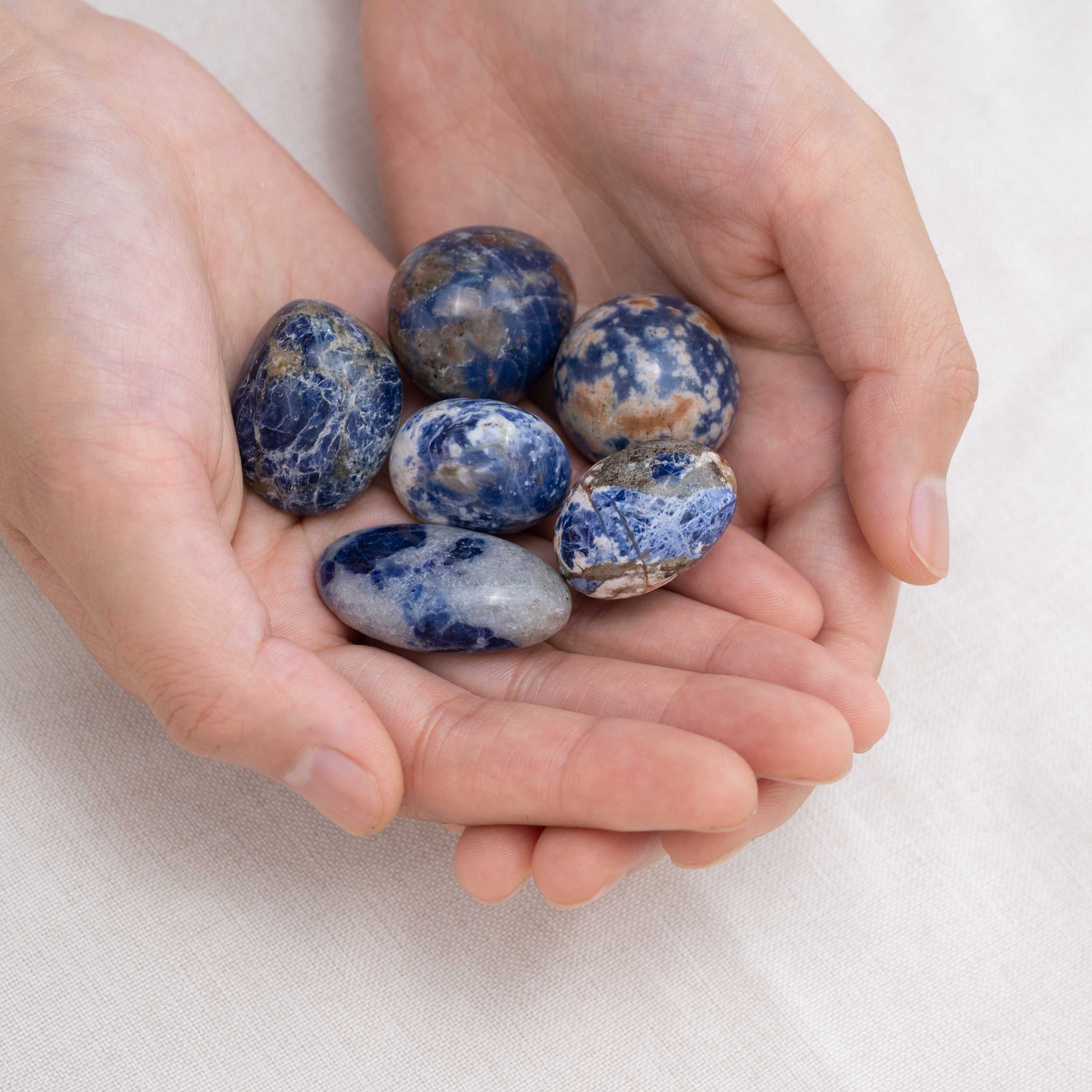 Hand cupping Sodalite tumbled stone for mental clarity.