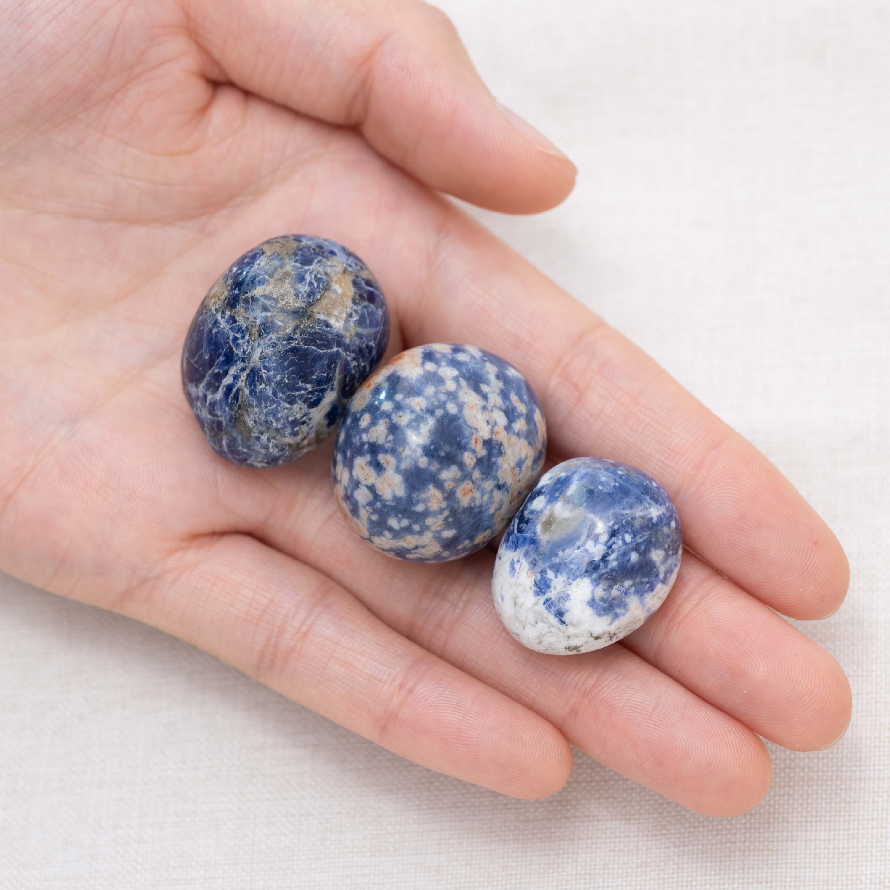 Hand holding Sodalite tumbled stone for wisdom and clarity.